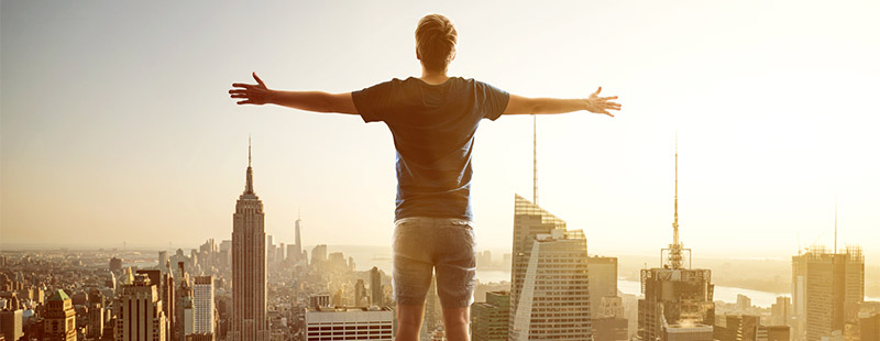 Ein Bild auf dem eine Person die Arme Austreckt und auf ein Land blickt