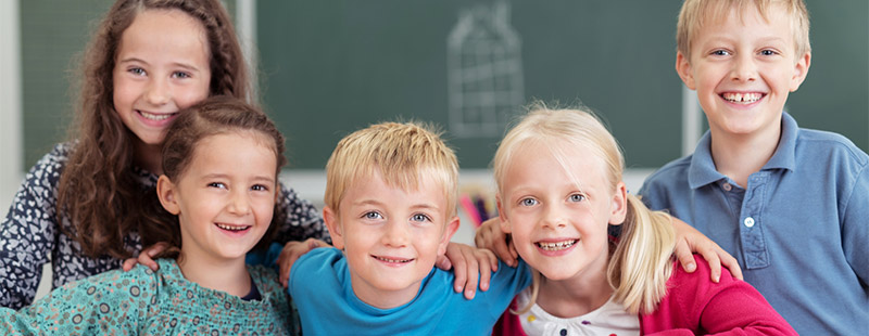 5 lächelnde Kinder die sich gegenseitig an den Schultern halten