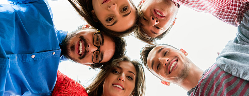 Eine Gruppe von Menschen die die Köpfe zusammen stecken und einen Kreisbilden