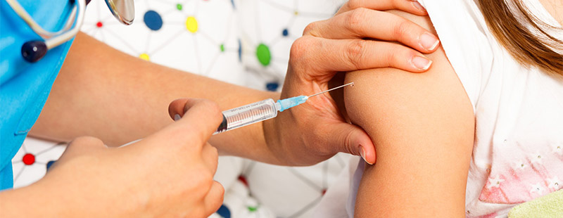 Ein Bild auf dem ein Kind eine Impfung erhält, eine Ärztin hält eine Spritze in der Hand