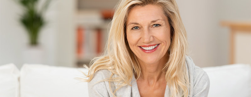 Eine lachende Frau mit rotem Lippenstift die auf einem Sofa sitzt