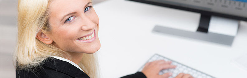 Eine lachende Frau die am PC arbeitet