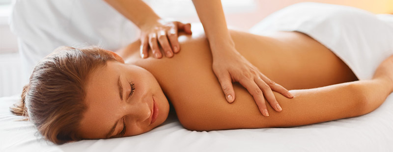 Eine Frau die Oberkörper frei mit dem Bauch auf einer Liege liegt und von einer anderen Frau eine Massage bekommt.