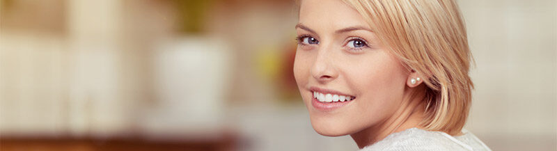 Eine Frau die lächelnd uns anschaut und die Hände verschränkt hat