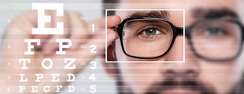 Ein Bild auf dem ein Mann mit einer Brille zu sehen ist, er sieht verschiedene Buchstaben und Zahlen zu lesen