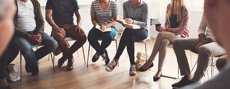 Ein Bild mit mehreren Personen die in einem Kreis sitzen.