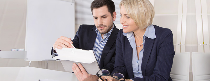 Ein Bild auf dem zwei Mitarbeiter in ein Tablett schauen und etwas gemeinsam besprechen