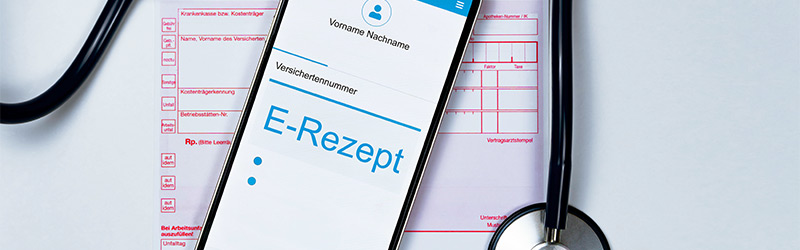 E-Rezept in der gematik App einlösen Ein Bild mit einem Rezept, auf dem Rezept liegt ein Handy mit dem Hinweis E-Rezept