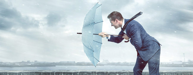 Ein Bild auf dem ein Mann mit einem Regenschirm gegen den Wind und den Regen kämpft